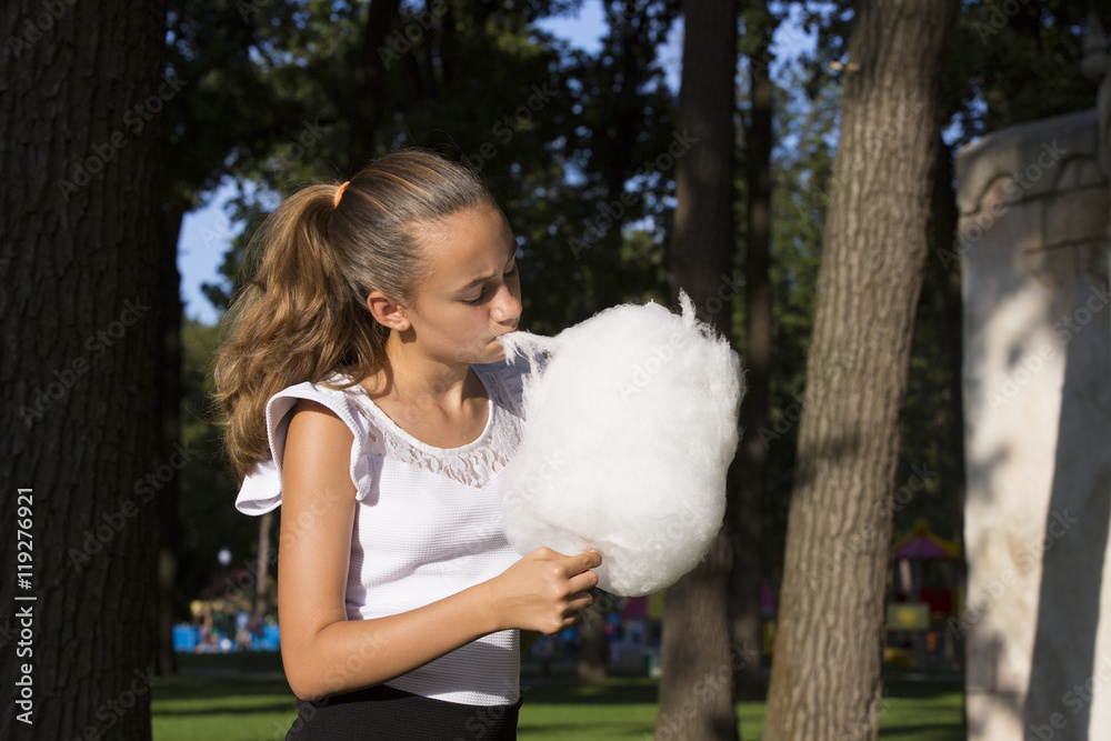 Girl eating cotton candy in a summer park Girl eating cotton candy in a summer park