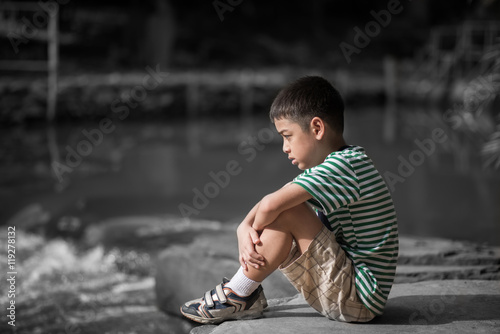 Photos Little boy sitting on the rock looking at waterfall alone color spot