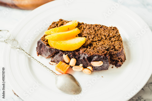 piece of chocolate cake with pumpkin, nuts and fresh peaches on