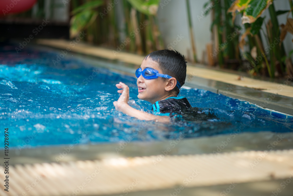 Little mix Asian Arab boy swimming at swimming pool in the hotel outdoor activity