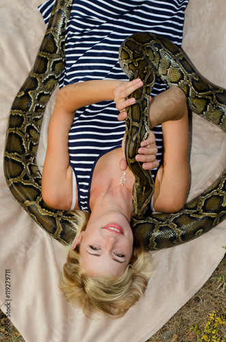Portrait of a beautiful young girl with snake in a forest 