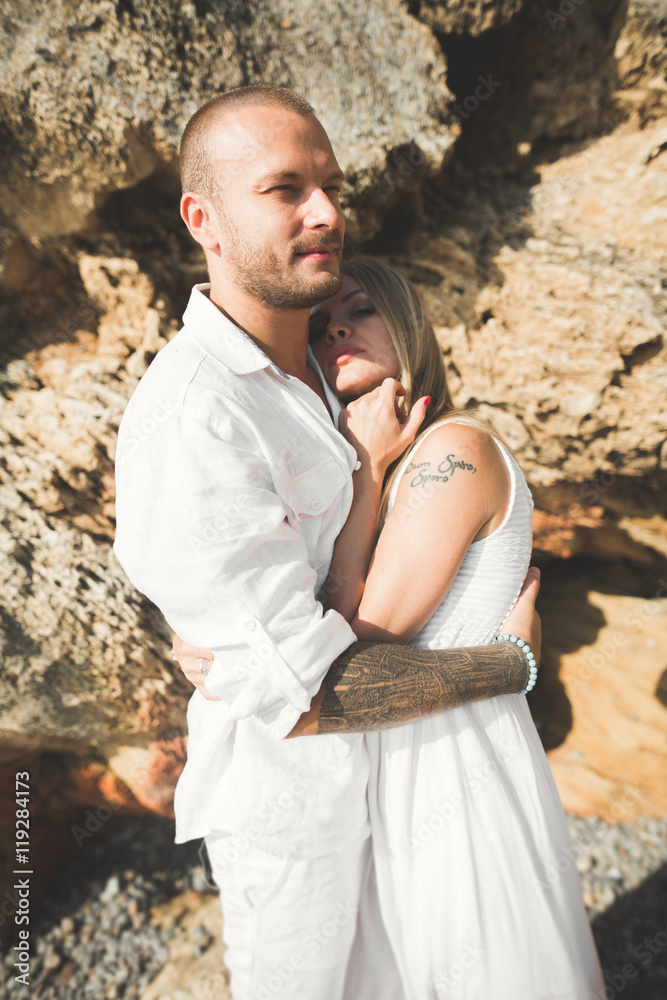 Young models couple posing on the beach with stones Young models couple posing on the beach with stones
