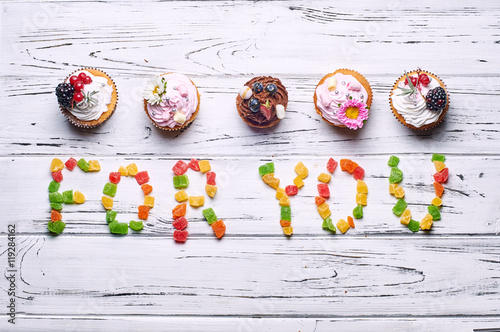Beautiful cakes and candied fruit on a white wooden table. Table with food for the holiday.