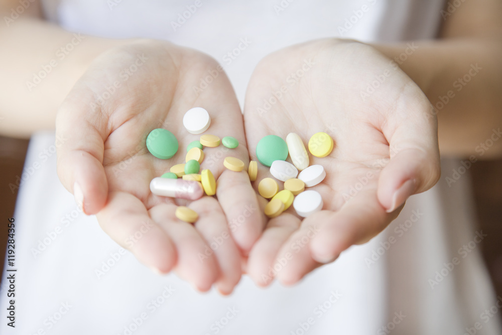 Woman is holding a lot of different pills in both her hands Woman is holding a lot of different pills in both her hands