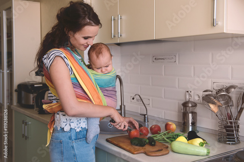 Young mom cooking in the kitchen with the baby. Vegetarian healthy food. Healthy food breastfeeding mothers.