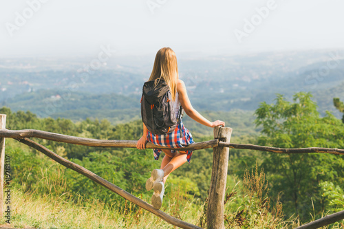 Wallpaper Mural Young female hiker with backpack sitting on the fence and enjoy the view. Torontodigital.ca