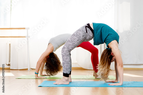 Two young girls doing back bend pose in yoga class photo