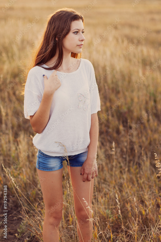 Young girl with long brown hair stay at the meadow. Young girl with long brown hair stay at the meadow.