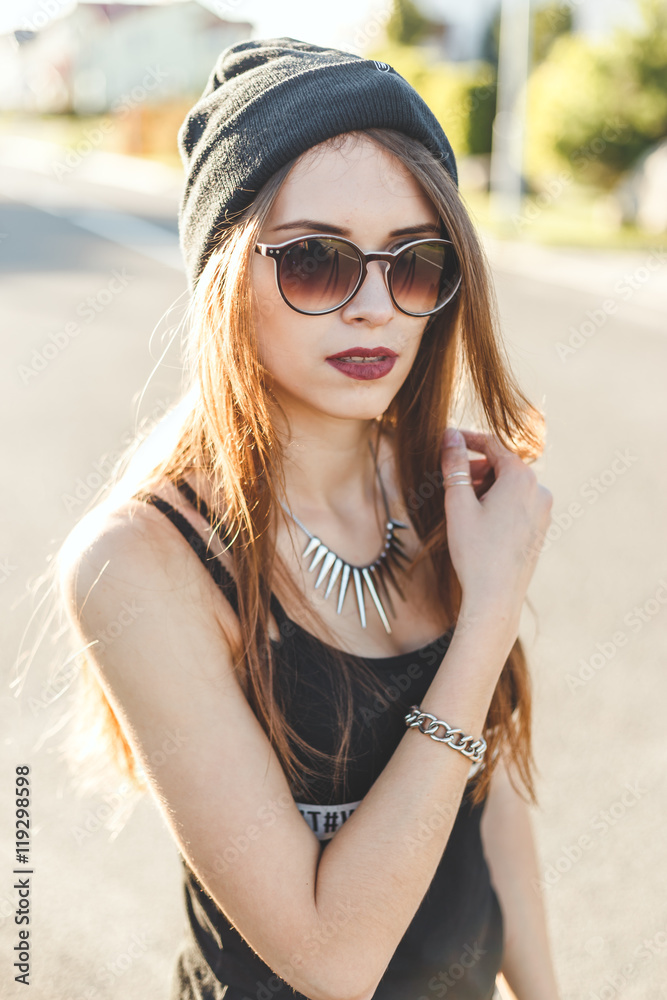 portrait of a young stylish hipster girl dressed in dark  cap and sunglasses