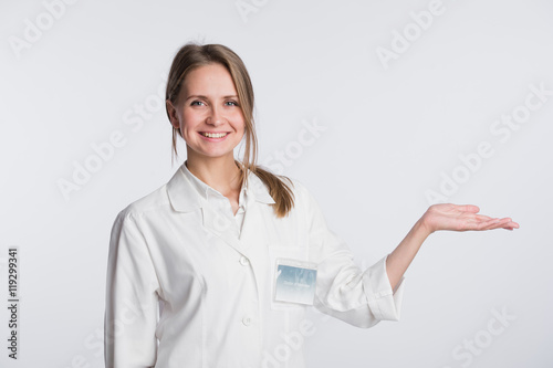 Young doctor woman nurse presenting and showing copy space for product or text. Caucasian female medical professional isolated on white background.