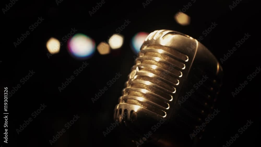 Concert vintage glare microphone on stage in empty retro club under spotlight. Close up.