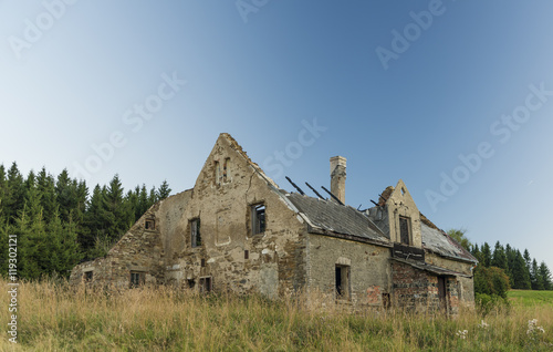 Old ruin of house on meadow after sunset photo
