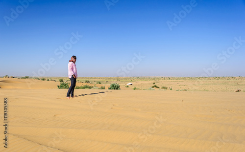Mature, young Indian lady tourist standing in barefoot in sand,