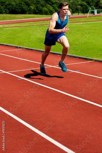 Man running on track at sport stadium. © stockyimages
