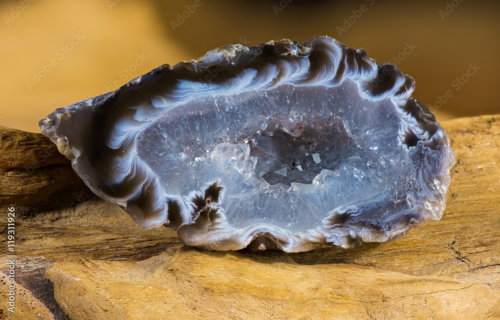 Eine Druse aus Achat und Quartz wurde geteilt, geschliffen und liegt auf einem Naturholz Eine Druse aus Achat und Quartz wurde geteilt, geschliffen und liegt auf einem Naturholz