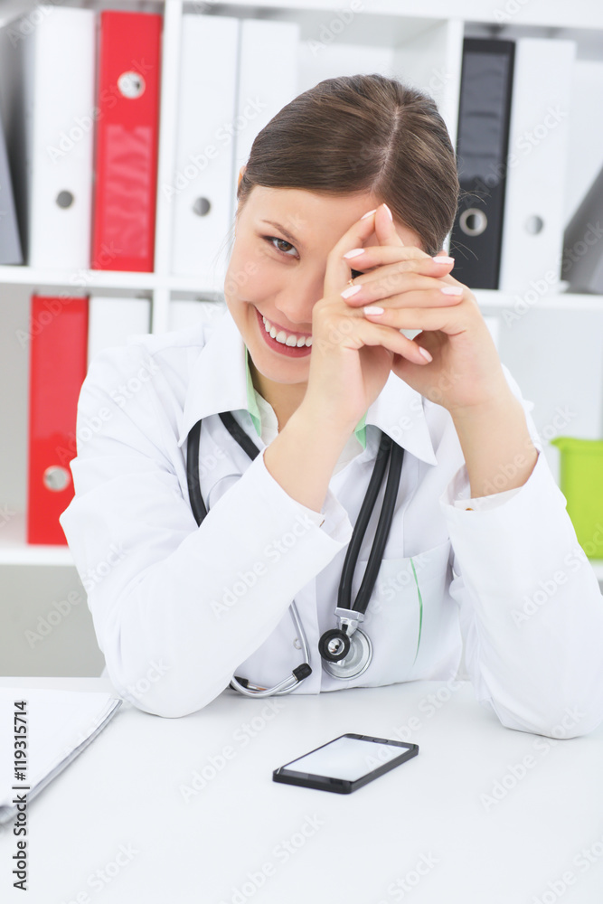 Young confident female medicine doctor smiling at her workplace in clinic.