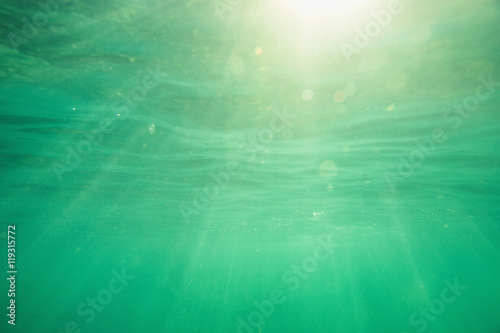 Underwater shot with sunrays and bubbles in deep tropical sea