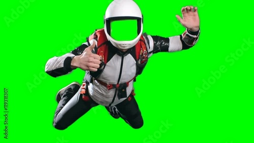 No face template for video editing, slow motion shot of skydiver flying in mid air, with his arms spread and gesturing thumb up looking at camera against green screen background, chroma key