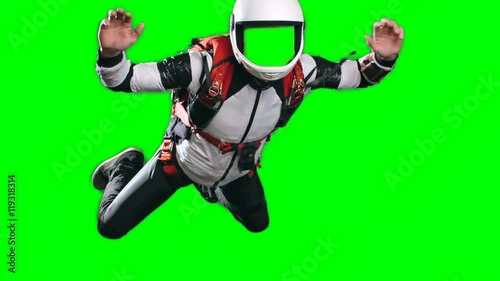 No face chroma key template for video editing, slow-motion shot of young man parachutist in full gear, white helmet, jumpsuit and harness, performing free fall against green screen background