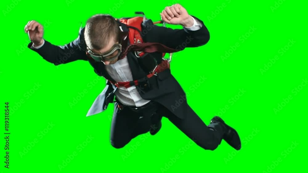 Concept of taking risks in business, worried man with parachute wearing formal suit and aviator mask in free fall looking down and moving up out of frame, chroma key green screen background