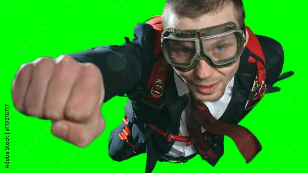 Closeup shot of confident self-assured businessman flying in superman pose wearing formal suit and aviator goggles, going fast to success with parachute on his back, chroma key green screen background Closeup shot of confident self-assured businessman flying in superman pose wearing formal suit and aviator goggles, going fast to success with parachute on his back, chroma key green screen background