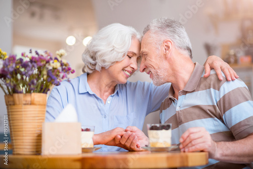 Pleasant delighted senior couple bonding to each other.