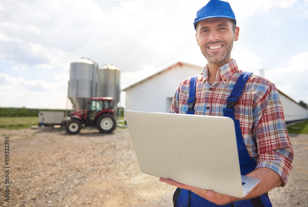 Fototapeta premium Farmer with laptop and his farm.