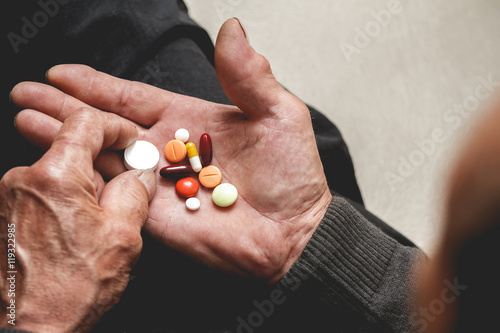 Many multi-colored pills in a Senior's hands. Painful old age. Caring for the health of the elderly photo