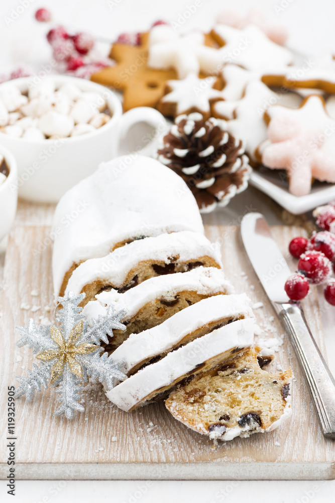 Christmas Stollen on a wooden board and cookies, vertical