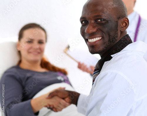 Black male doctor shake hands as hello with female patient