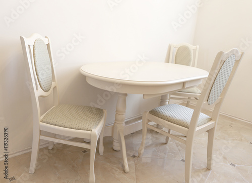 Beige classical dining room with roung table and chairs closed to the wall