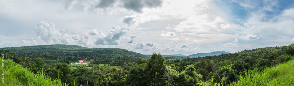 Broad panorama of the countryside in Thailand with green field in foreground.