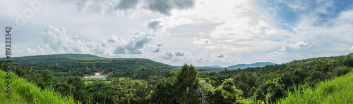 Broad panorama of the countryside in Thailand with green field in foreground.