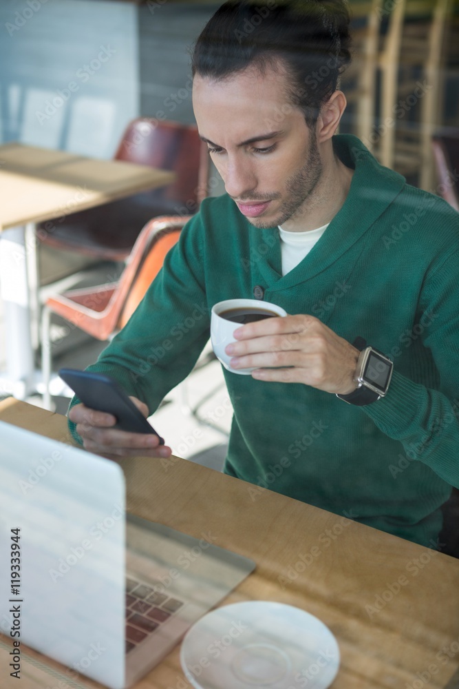 Man using mobile phone while having cup of coffee Man using mobile phone while having cup of coffee