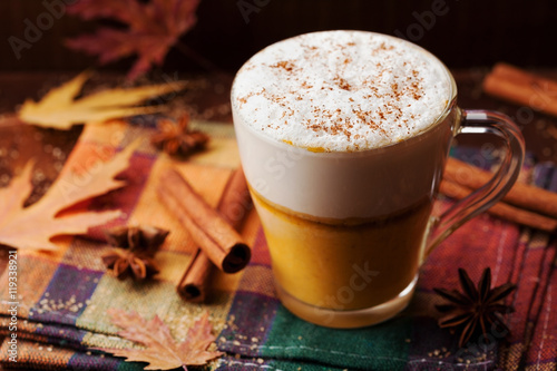 Pumpkin spiced latte or coffee in a glass on a vintage table. Autumn or winter hot drink.