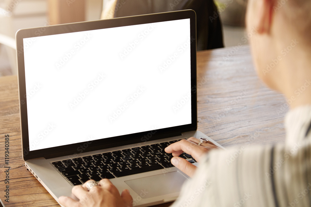 Rear view of female student of higher education institution using generic laptop for working on her diploma. Young businesswoman typing message on computer keyboard, checking email. Selective focus Rear view of female student of higher education institution using generic laptop for working on her diploma. Young businesswoman typing message on computer keyboard, checking email. Selective focus