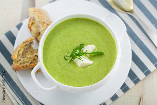Broccoli cream soup with bread on a table. Classic European food. Top view. Close-up shot..