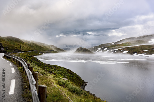 Norway, Hedmark, Tufsindalen valley, road, Gomma river and clouds in spring photo