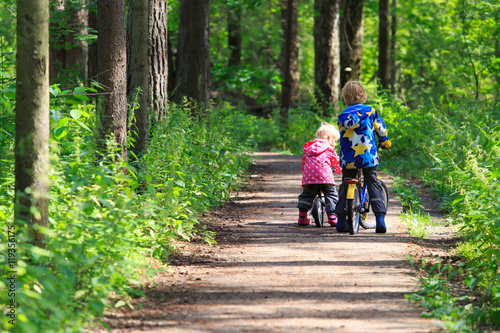 kids sport - little boy and girl riding bikes in forest