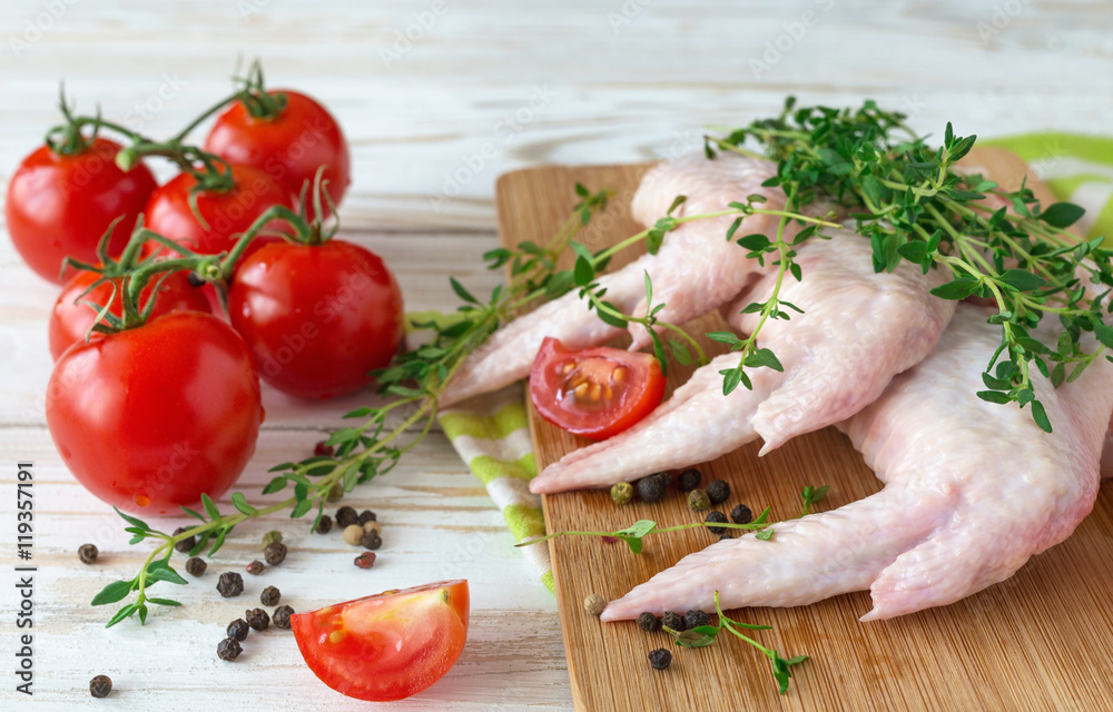 Raw chicken wings with thyme, chili, pepper and tomatoes Raw chicken wings with thyme, chili, pepper and tomatoes