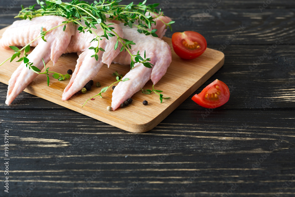 Raw chicken wings with thyme, chili, pepper and tomatoes Raw chicken wings with thyme, chili, pepper and tomatoes