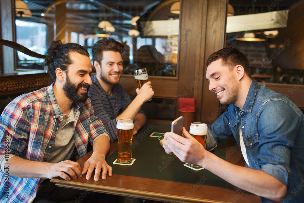 male friends with smartphone drinking beer at bar male friends with smartphone drinking beer at bar