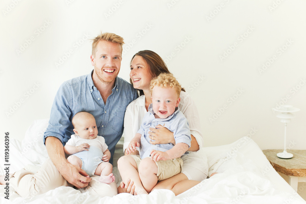 Happy parents with two sons sitting on bed Happy parents with two sons sitting on bed