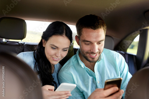 man and woman with smartphones driving in car © Syda Productions