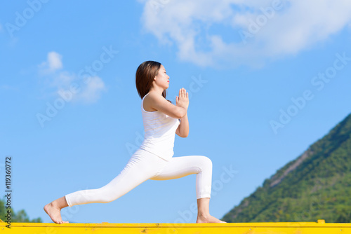 Young woman does yoga exercise outdoors.