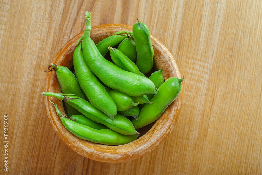 Bowl of fresh podded broad beans on a wooden table. Healthy organic food. Bowl of fresh podded broad beans on a wooden table. Healthy organic food.