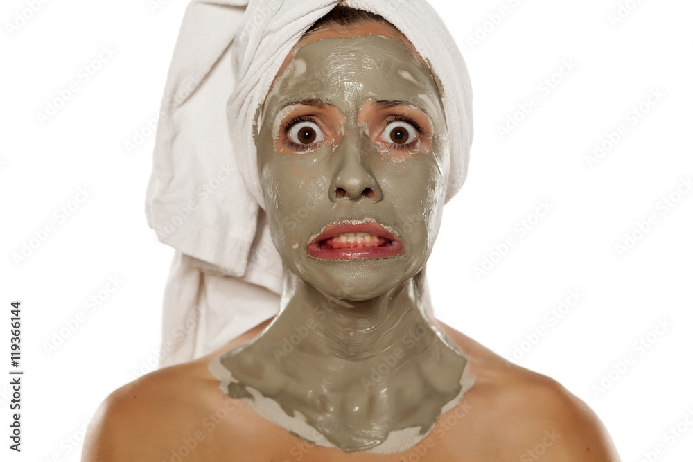 young shocked woman with a towel on her head applied a mud mask on her face young shocked woman with a towel on her head applied a mud mask on her face