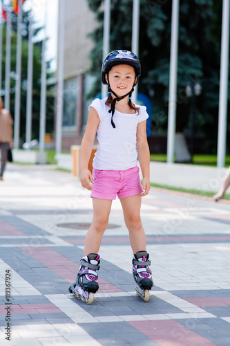 Little girl on roller skates in helmet at a park