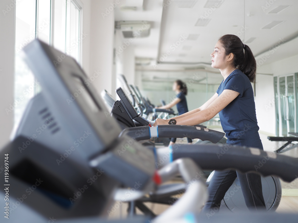 Asian woman walking,  running on treadmill gym workout.