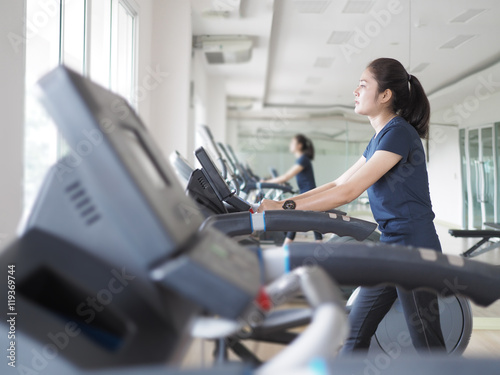 Asian woman walking, running on treadmill gym workout.